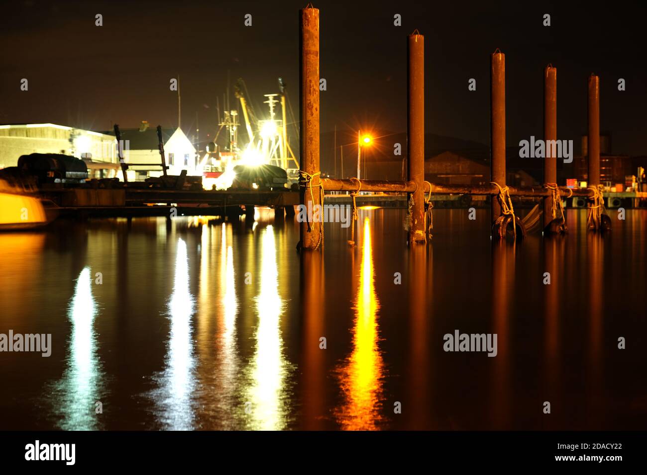 Tyres and rope hanging on metal post in Arklow harbour at night. Stock Photo