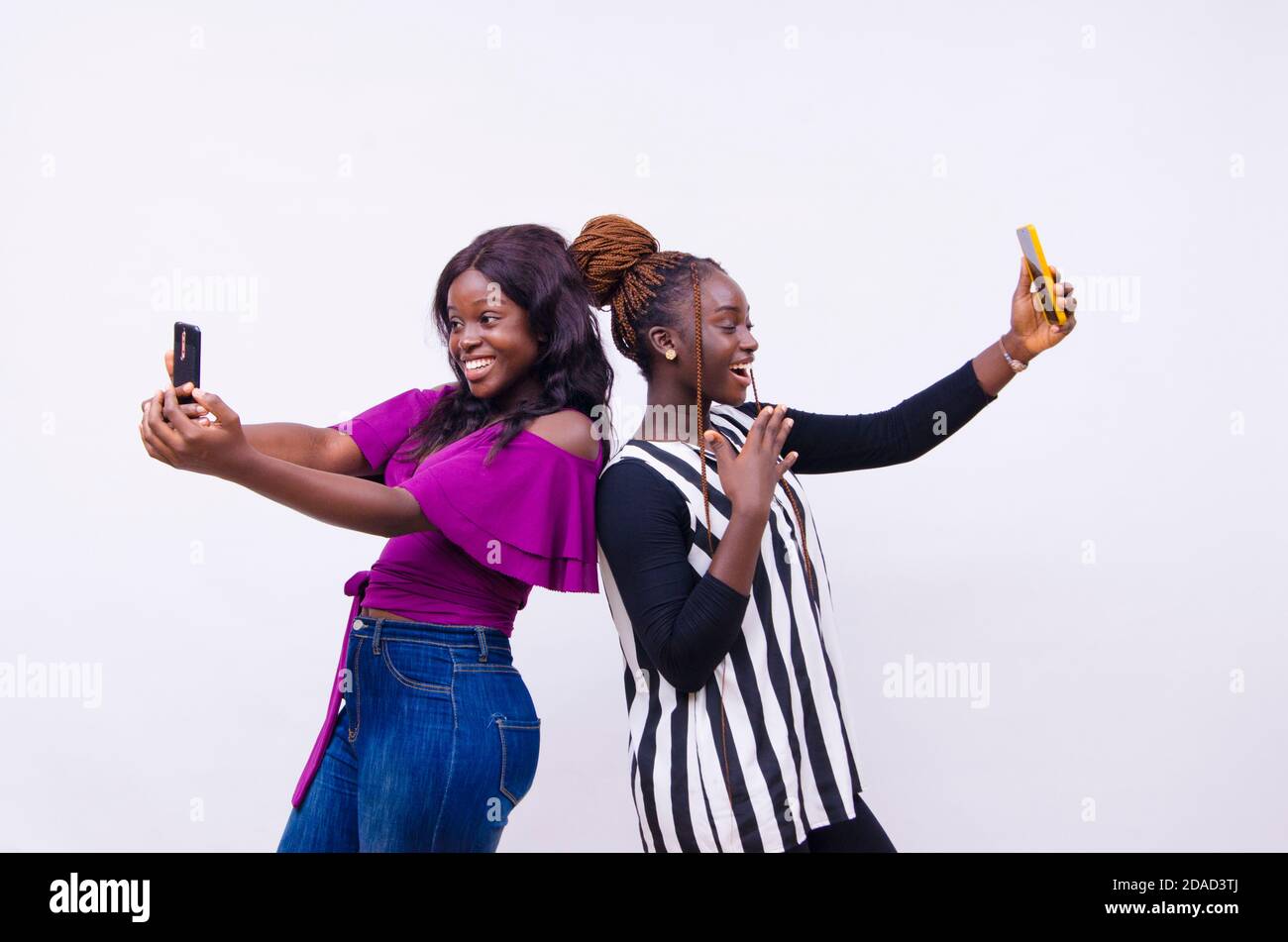 two young black sisters holding up smart phones Stock Photo