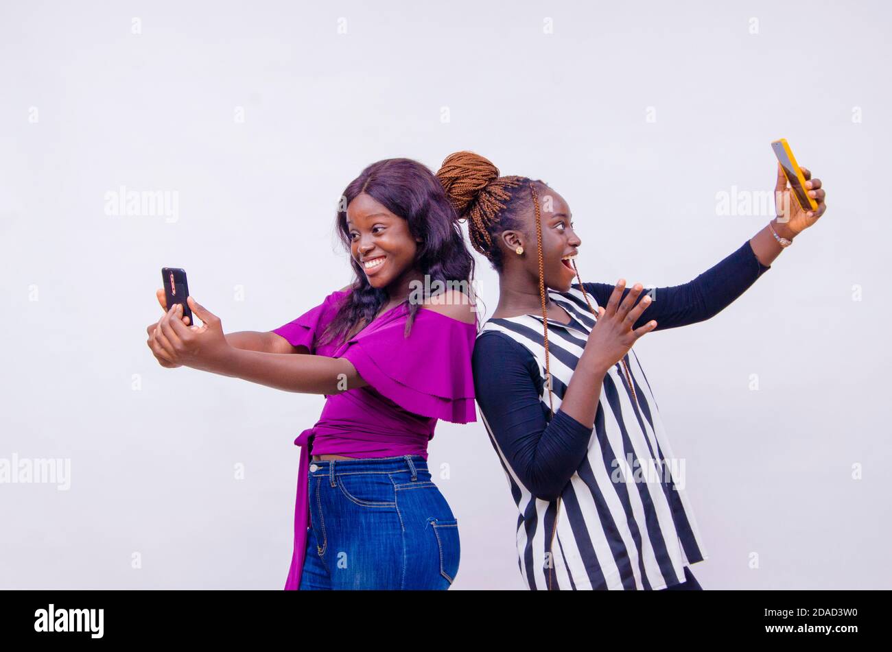 two young black sisters holding up smart phones Stock Photo