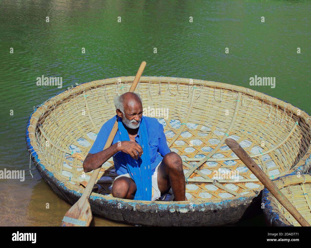 the old boatman sitting on his coracle boat, boating point of hogenakkal in tamil nadu, india Stock Photo