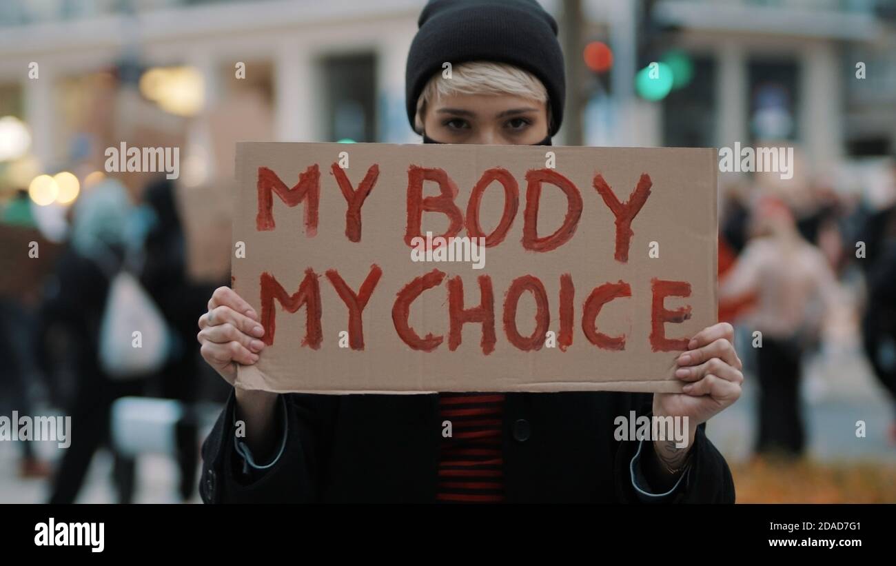 Woman holding a sign My Body, My Choice. Protest against tightening of the abortion law . Nationwide women's strike. Wearing protective face mask against COVID-19 Coronavirus. High quality photo Stock Photo