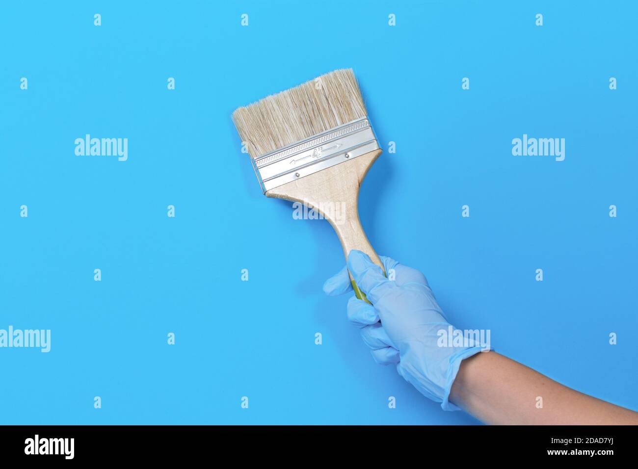 Brush for paint in hand on a blue background. Paint brush with wooden