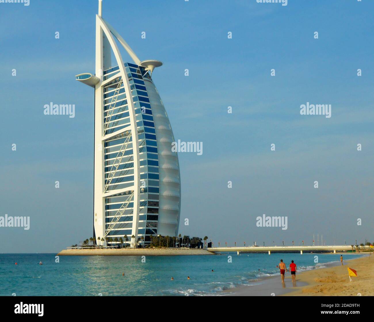 People in the sea and on the beach in front of the Burj Al Arab building in Dubai UAE Stock Photo