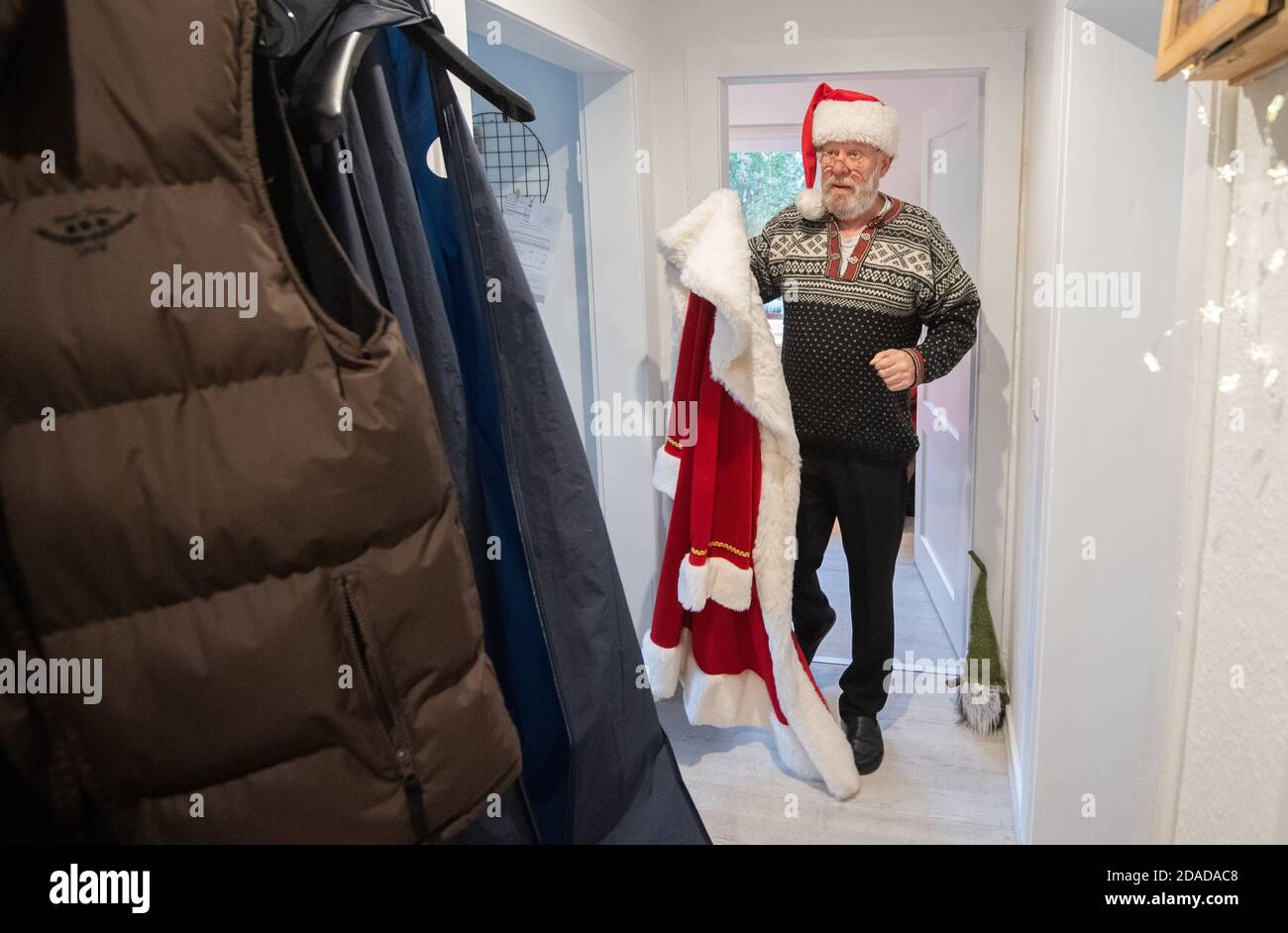 Celle, Germany. 11th Nov, 2020. Willi Dahmen, professional Santa Claus actor, hangs a coat on the wardrobe of his apartment. This year, the Corona pandemic is putting hundreds of rented Santa Clauses in Germany out of work. Credit: Julian Stratenschulte/dpa/Alamy Live News Stock Photo