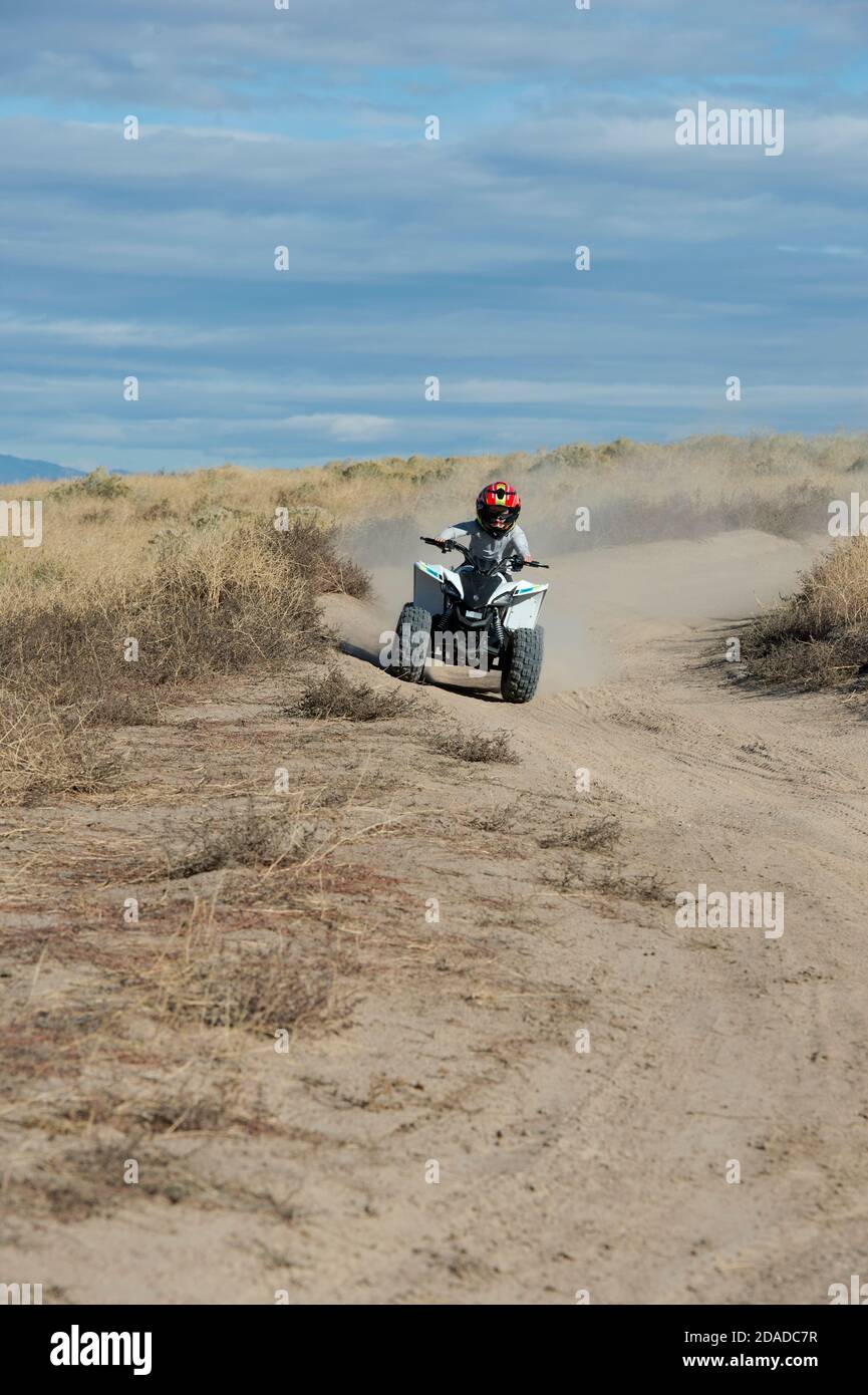 Pre-teen riding mini-AtV on a dirt track in Ada County, Idaho, USA Stock Photo