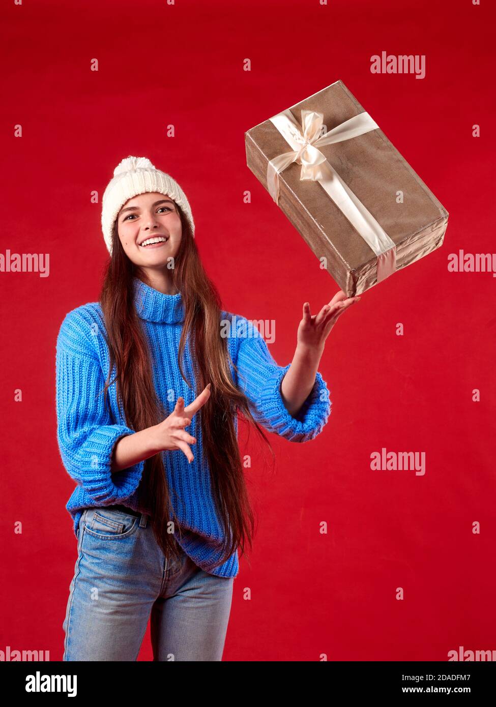 girl in blue coffee catches gifts in the air on a red background. Stock Photo