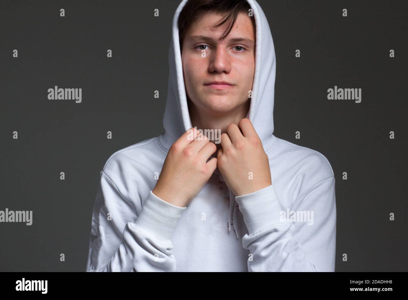 a boy in a white hoodie with a hood on. Studio portrait on a black background Stock Photo