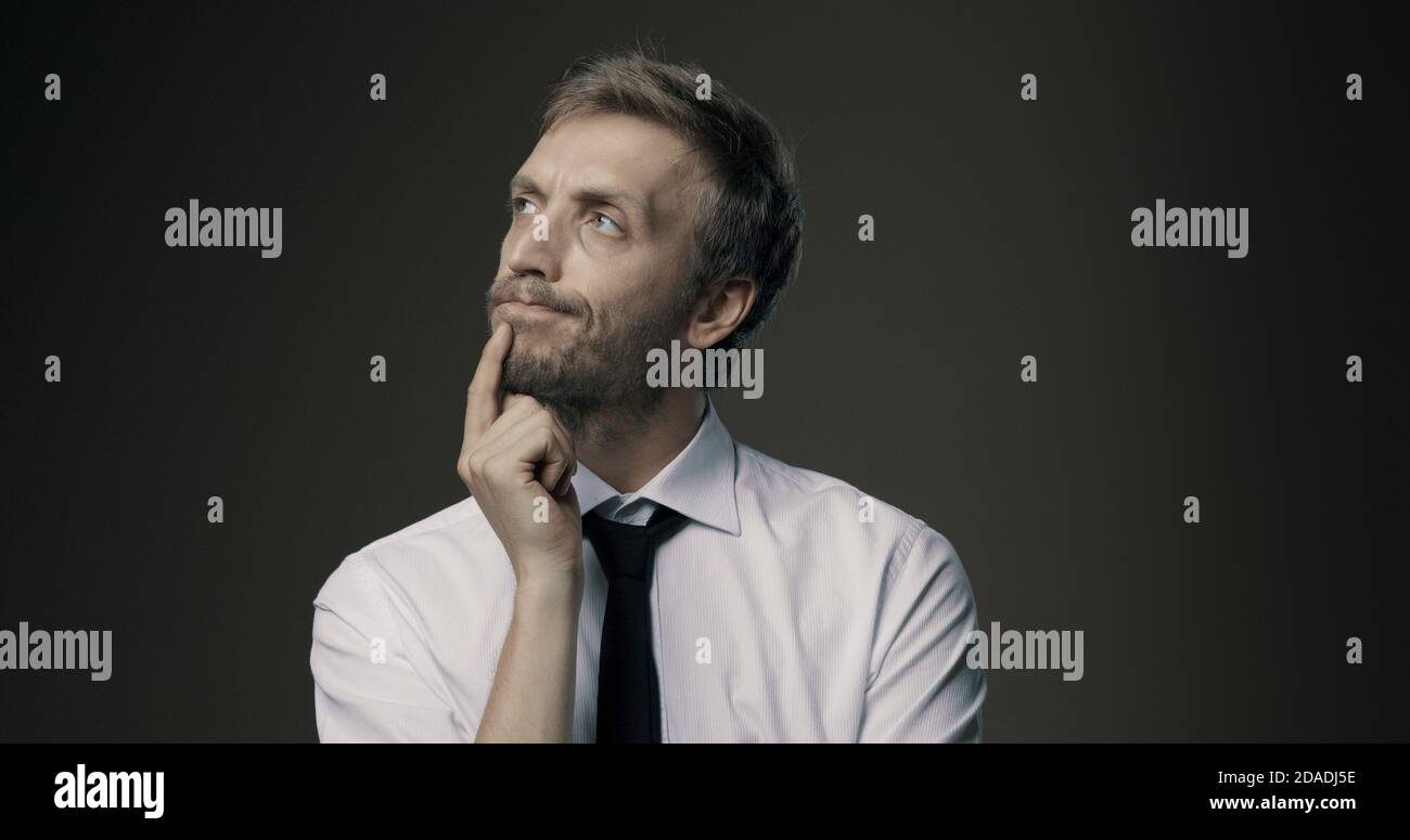 Pensive businessman thinking with hand on chin, problem solving and decisions concept Stock Photo