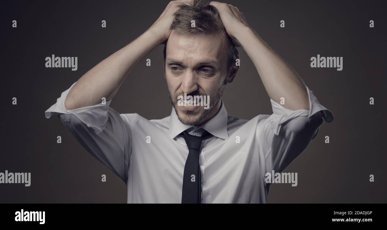 Disappointed businessman with head in hands, he has made a mistake and he is panicking Stock Photo