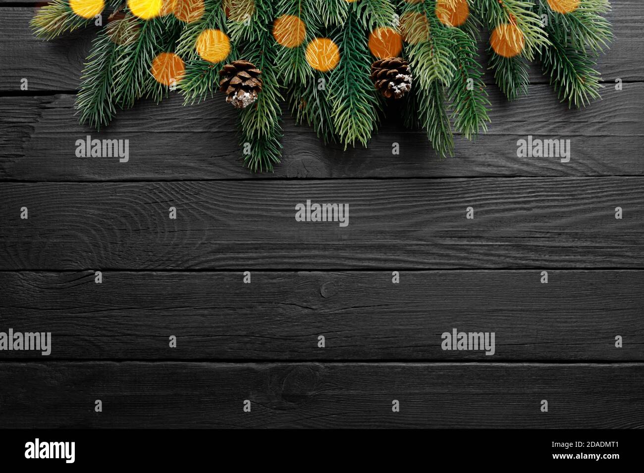Christmas border with fir branches and cones on black wooden background ...