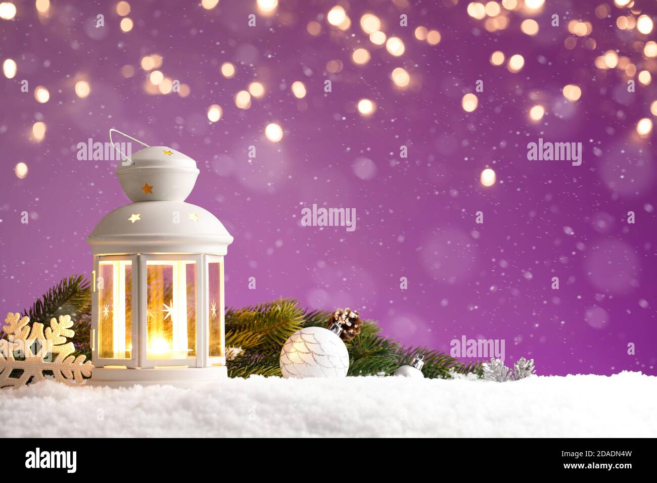 Christmas lantern with decorations on purple background with golden lights Stock Photo