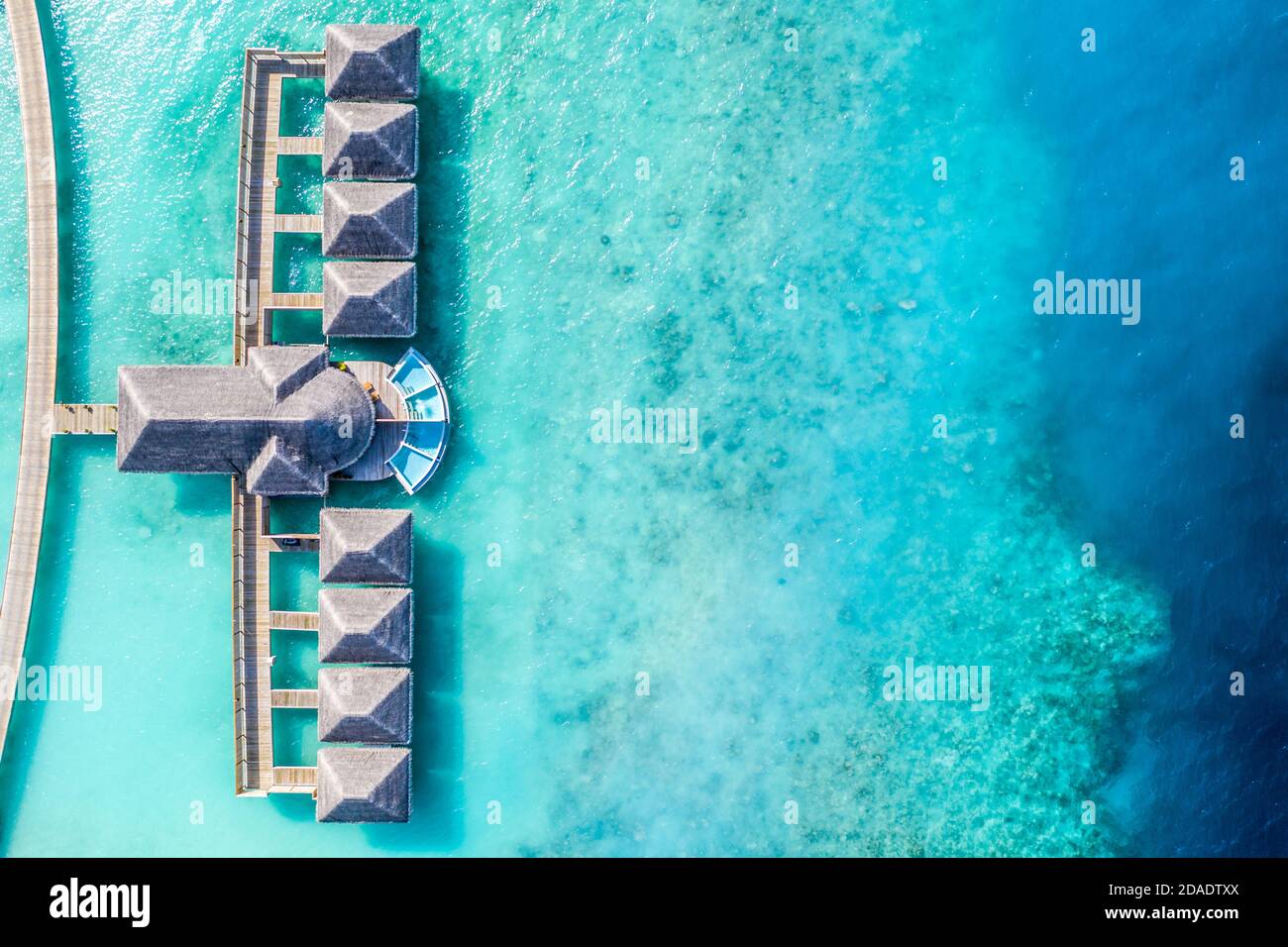 Atolls and islands in Maldives. Tropical island at Maldives with luxury water villas, bungalows over amazing blue sea. Summer vacation, aerial view Stock Photo