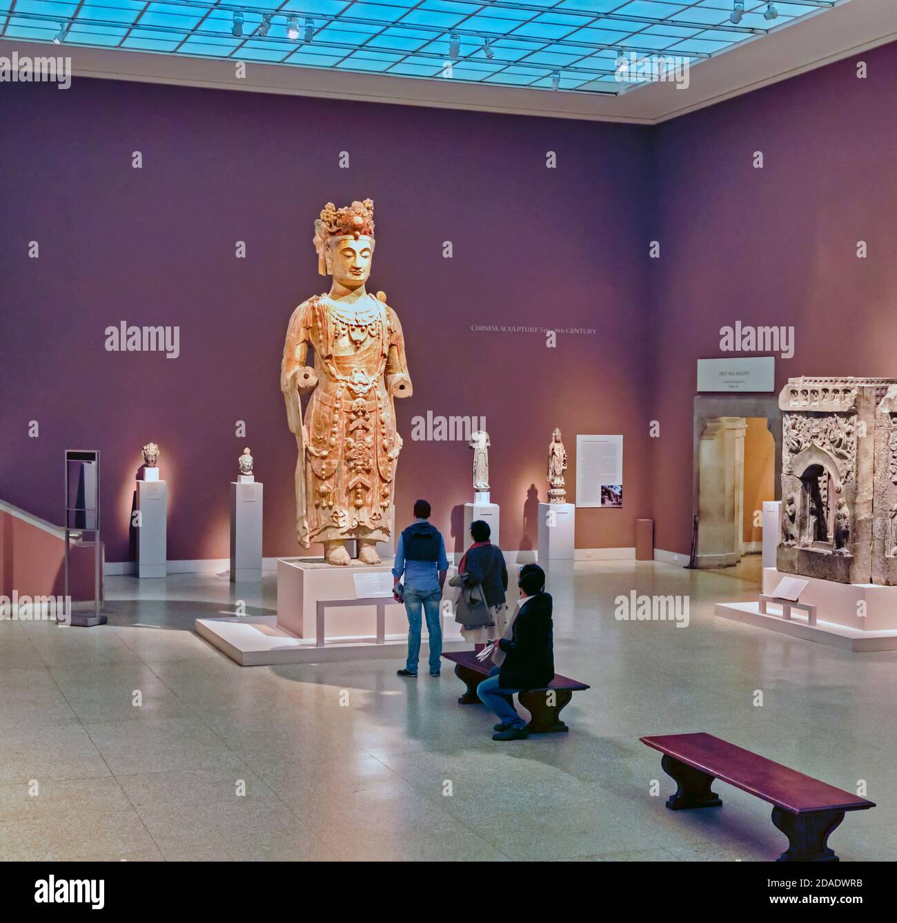 Visitors examining large scale Chinese sculpture of a Bodhisattva, probably Avalokiteshvara, dating from circa 550-560.  Displayed in the Metropilitan Stock Photo