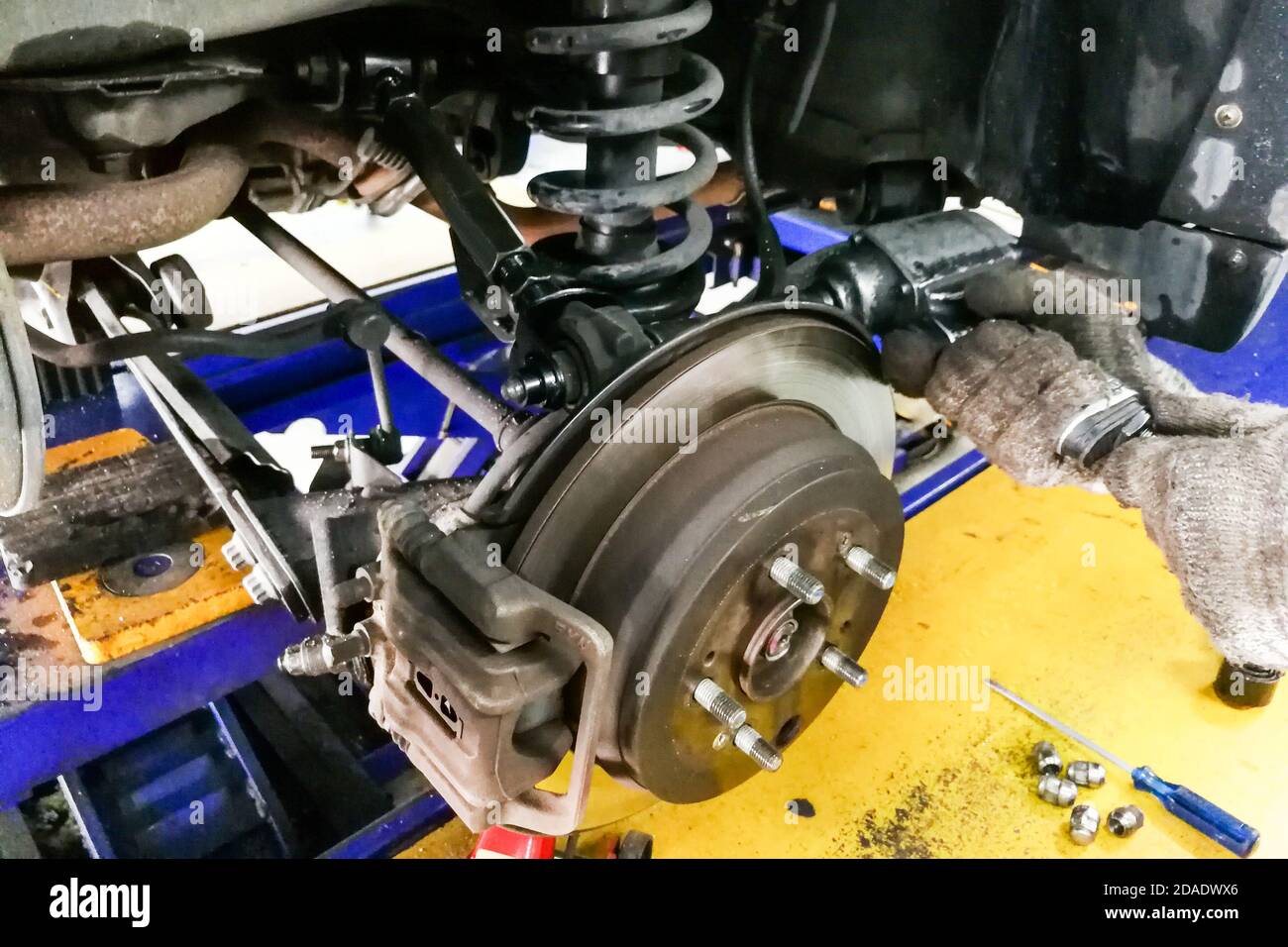 Mechanic adjusting car axle camber in during wheel alignment