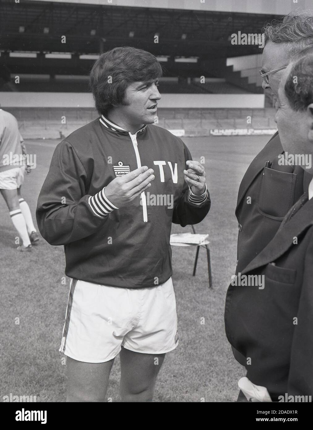 1976, historical, Terry Venables, the new Coach of Crystal Palace FC wearing a tracksuit top and shorts, talking to members of the press outside on the pitch at club's ground, Selhurst Park, Southeast London, England, UK. Venables would go on and win the Second Division championship with the club in 1979. Stock Photo