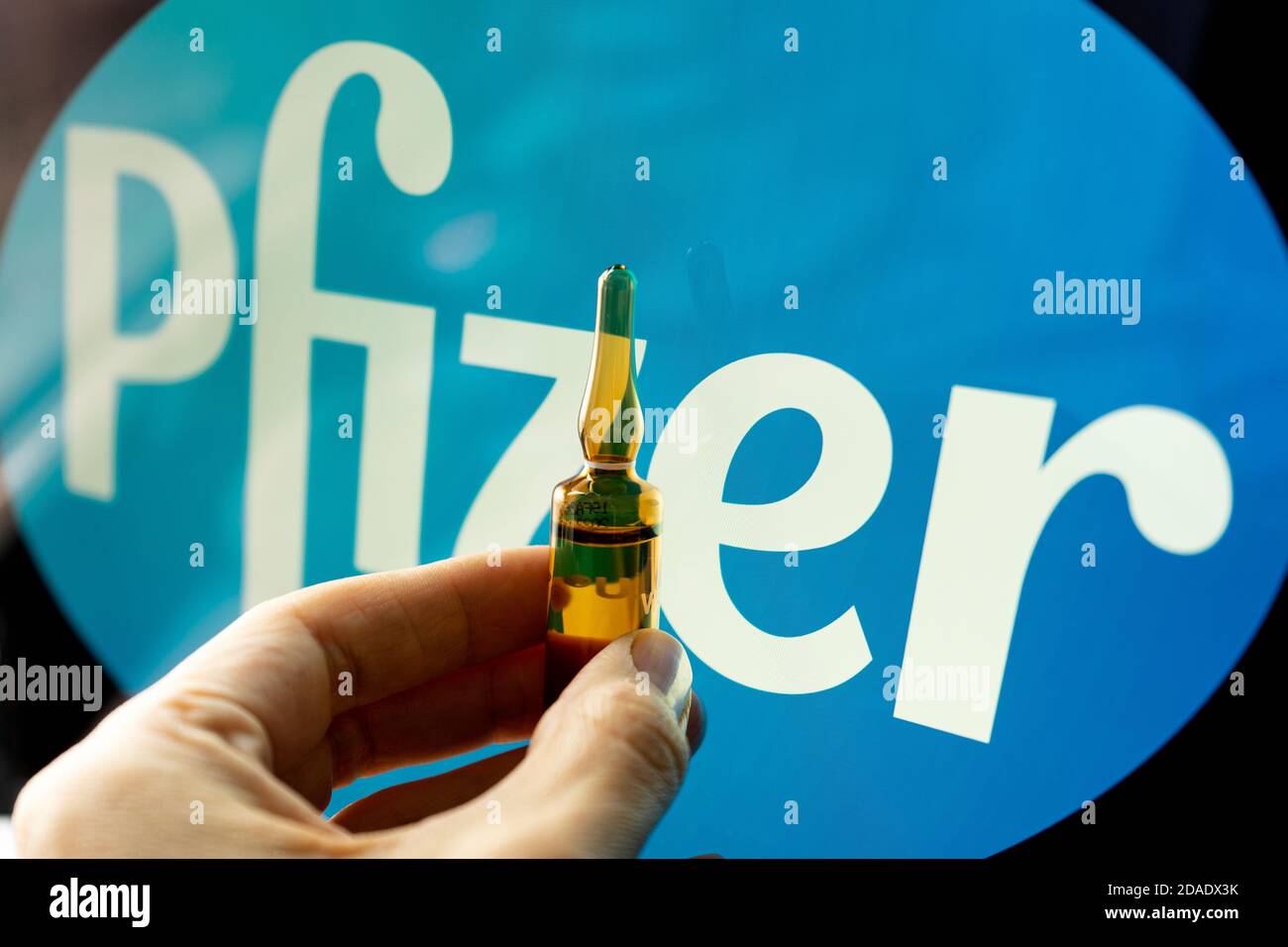 Pfizer coronavirus vaccine pharmaceutical corporation. Pfizer logo with hand holding vaccine. Stock Photo