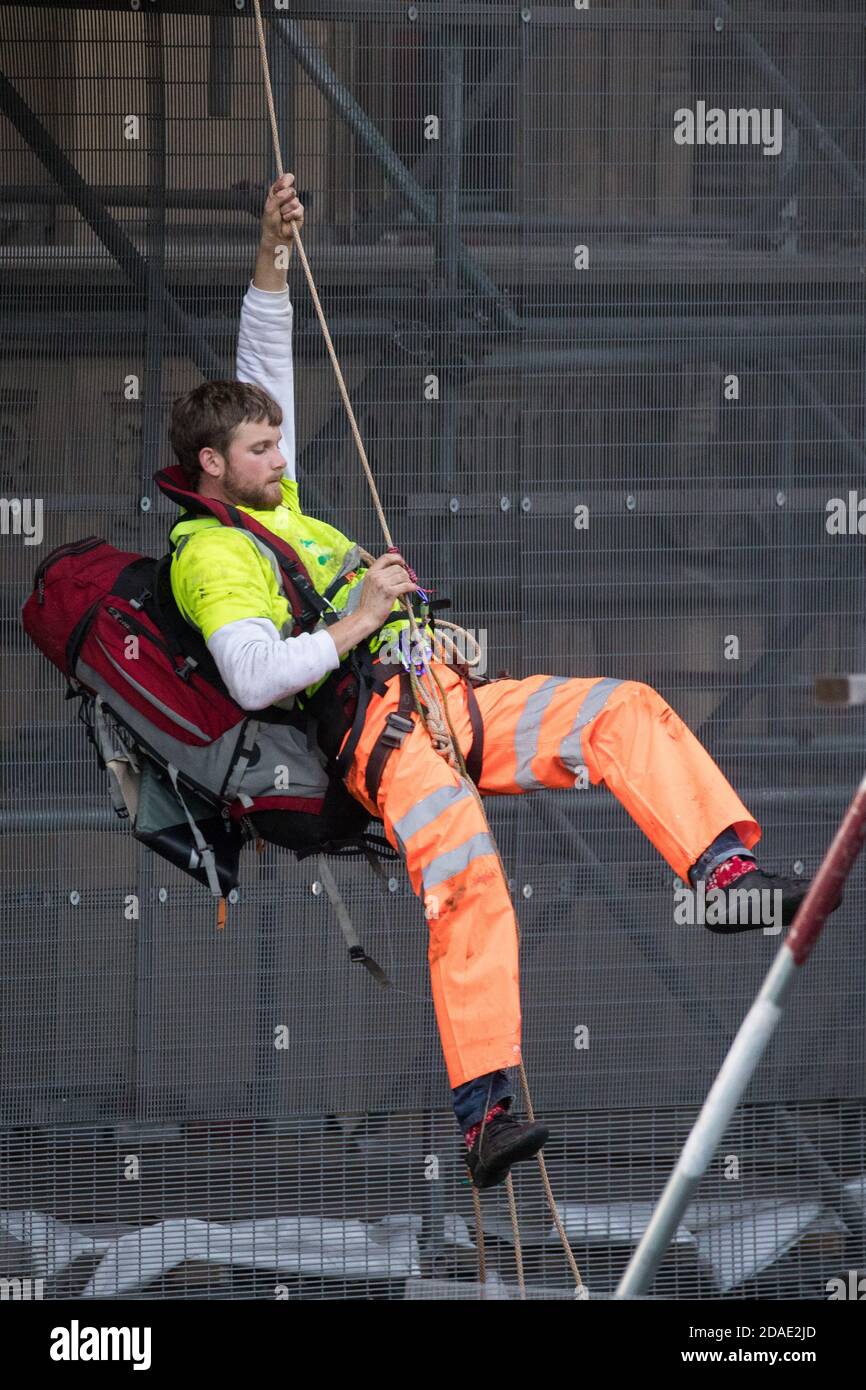 London, UK. 12th November, 2020. An activist from the group Action for Climate Truth and Reparations (ACTR) climbs scaffolding to hang an open letter to the UK people from Africans Rising For Justice, Peace and Dignity from the Houses of Parliament. The letter, which launches Africans Rising’s ReRight History campaign, contains a plea to the UK people to start making amends for the harm caused by slavery and colonialism.  Credit: Mark Kerrison/Alamy Live News Stock Photo