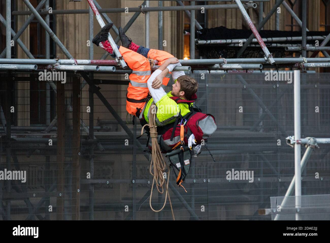 London, UK. 12th November, 2020. An activist from the group Action for Climate Truth and Reparations (ACTR) climbs scaffolding to hang an open letter to the UK people from Africans Rising For Justice, Peace and Dignity from the Houses of Parliament. The letter, which launches Africans Rising’s ReRight History campaign, contains a plea to the UK people to start making amends for the harm caused by slavery and colonialism.  Credit: Mark Kerrison/Alamy Live News Stock Photo