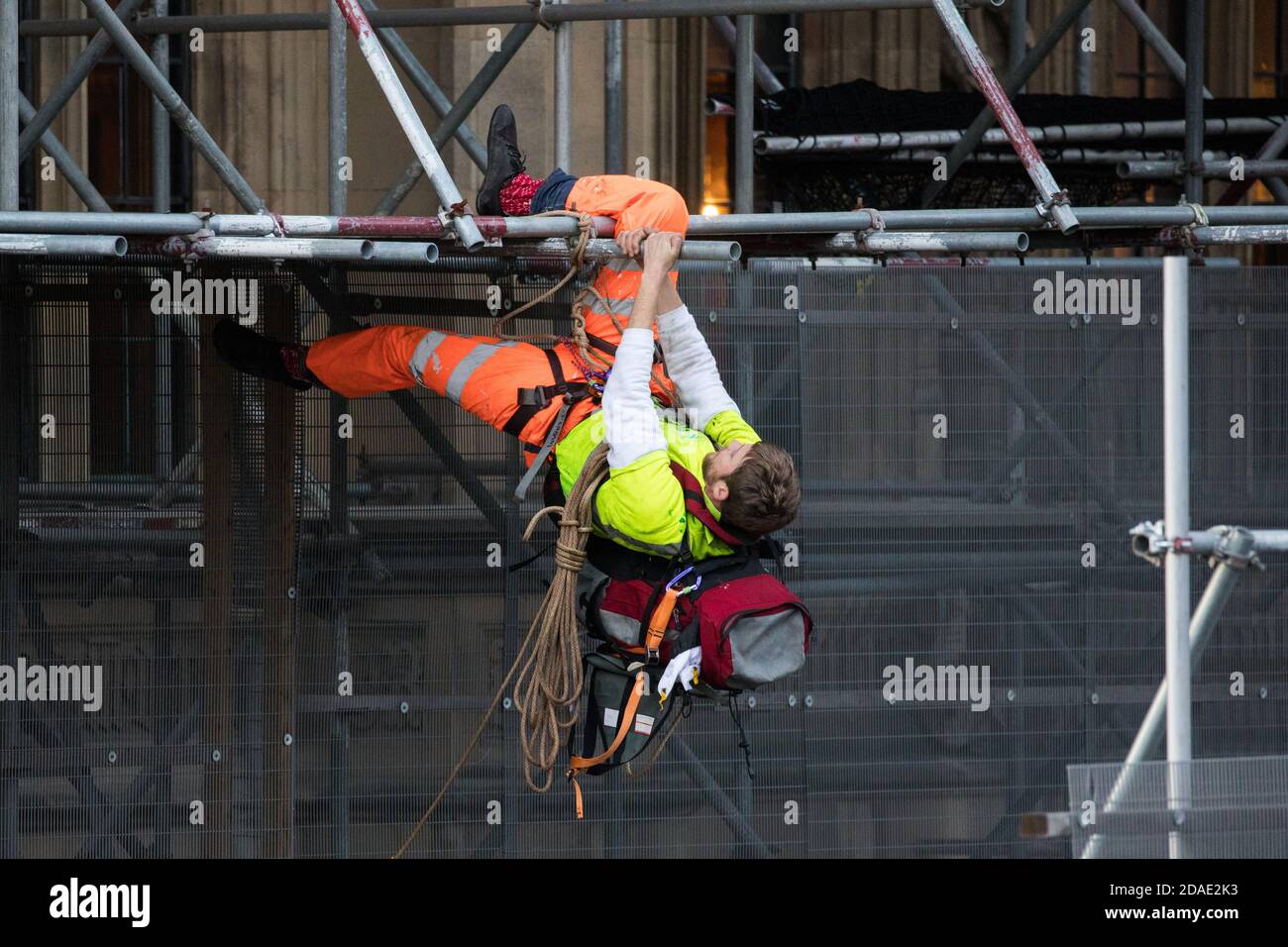 London, UK. 12th November, 2020. An activist from the group Action for Climate Truth and Reparations (ACTR) climbs scaffolding to hang an open letter to the UK people from Africans Rising For Justice, Peace and Dignity from the Houses of Parliament. The letter, which launches Africans Rising’s ReRight History campaign, contains a plea to the UK people to start making amends for the harm caused by slavery and colonialism.  Credit: Mark Kerrison/Alamy Live News Stock Photo