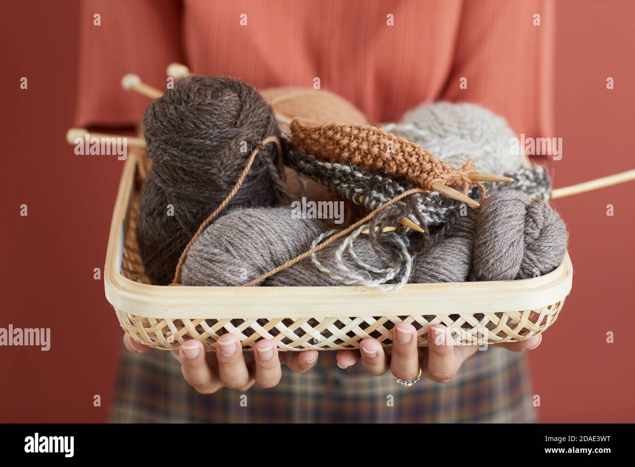 Close-up of woman holding basket with yarn and needles in her hands isolated on pink background Stock Photo