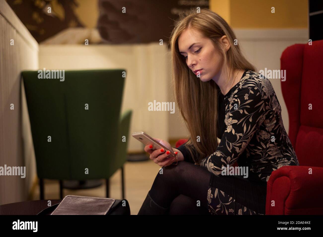 Young woman with long hair sitting in a red chair and talking on the ...