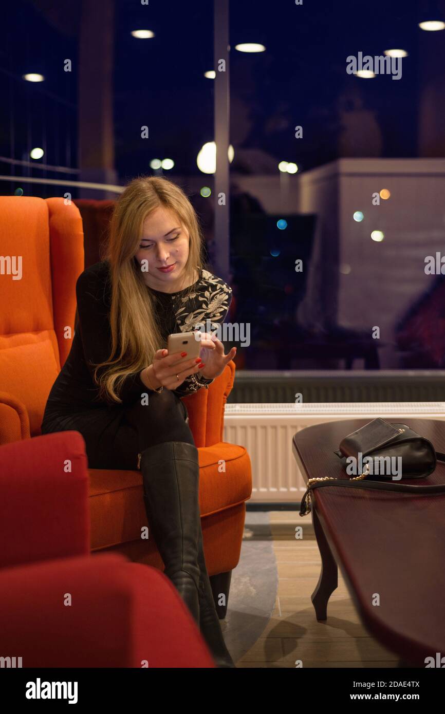 Young woman with long hair sitting in a red chair and talking on the ...