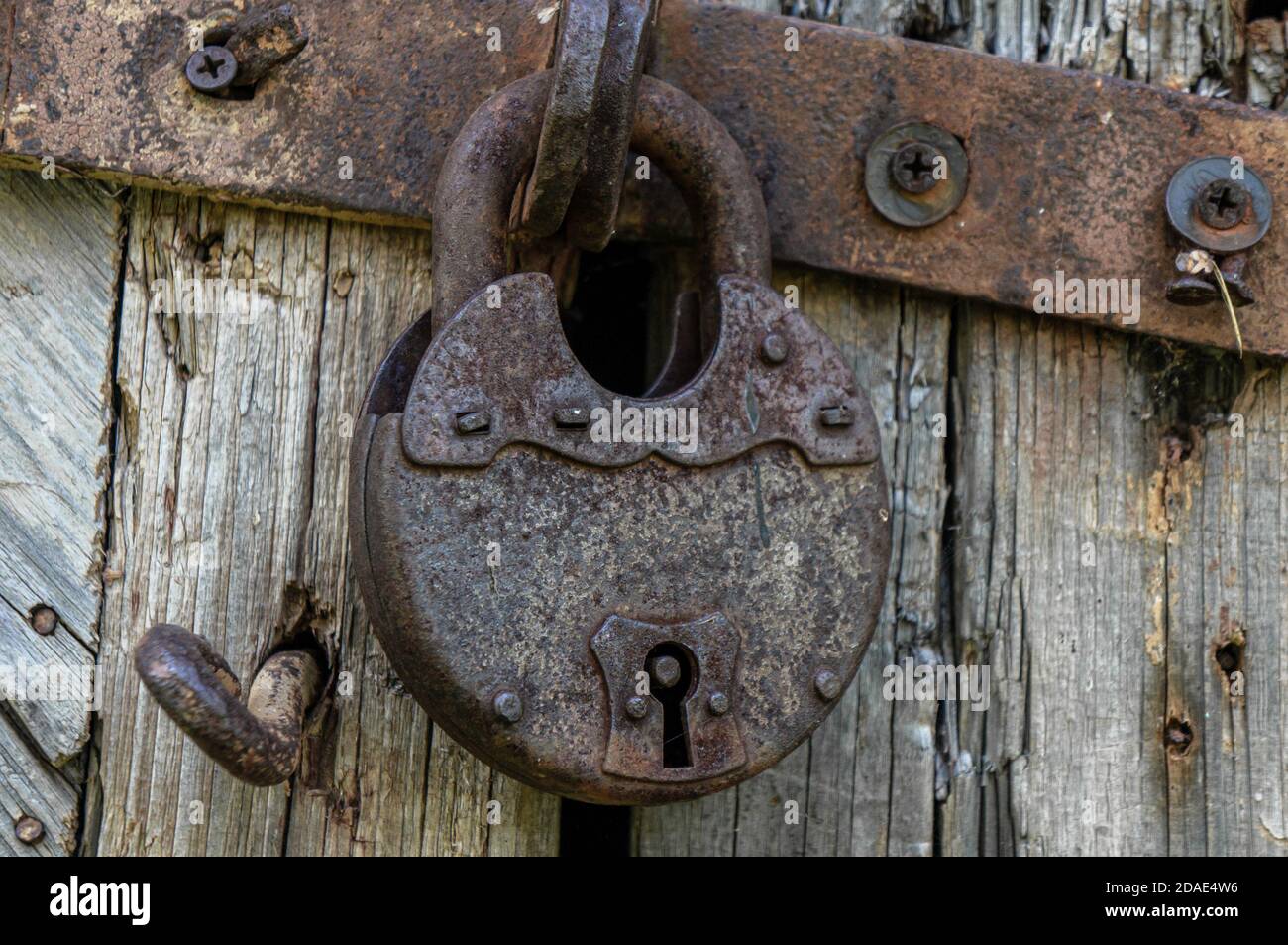 Old rust lock on the door. Metal lock on the gate of an old farmhouse. True  village style. Rust steel latch locked with iron lock Stock Photo - Alamy