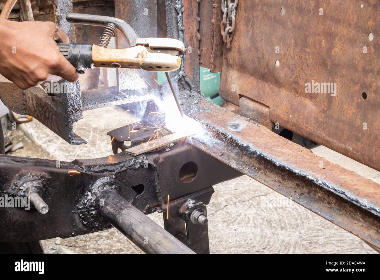 Hand of Welding Worker Welding Car Chassis or Car Metal Frame in Car Repair Shop Stock Photo