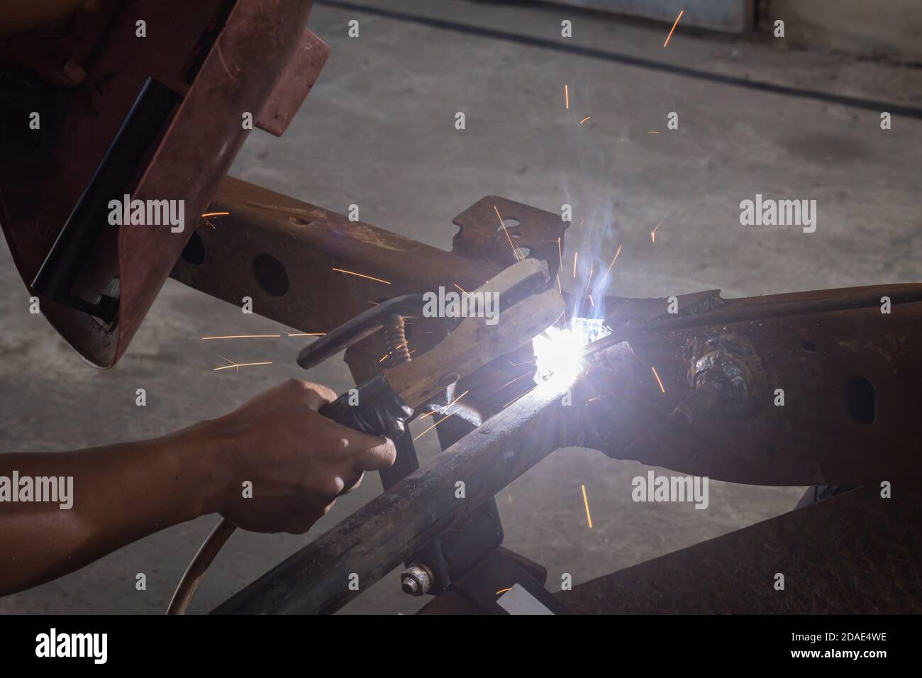 Hand of Welding Worker Hold Welding Mask and Welding Metal or Steel Construction of Car in Garage Stock Photo