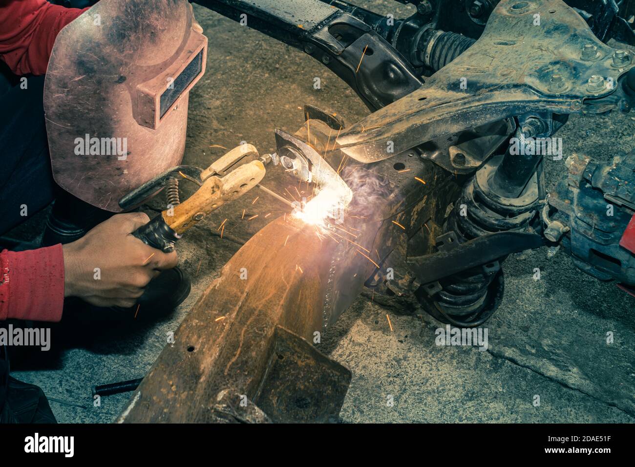 Hand of Welder Welding Metal or Steel of Car Construction in Garage on Top View in Vintage Tone Stock Photo