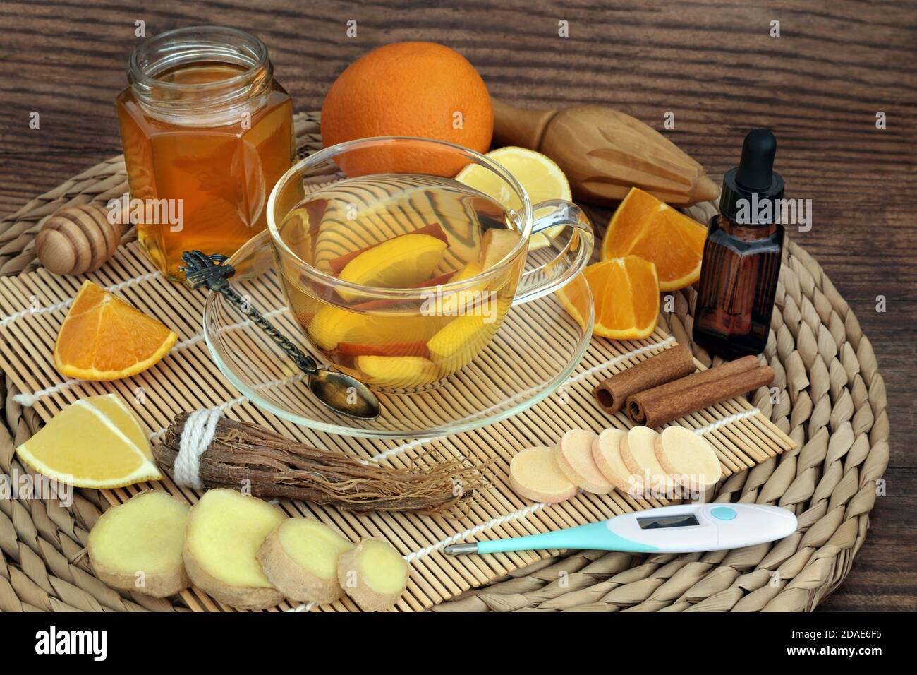 Home made remedy for cold & flu virus with hot herbal drink with fresh fruit & spices, eucalyptus essential oil with thermometer & vitamin C tablets. Stock Photo