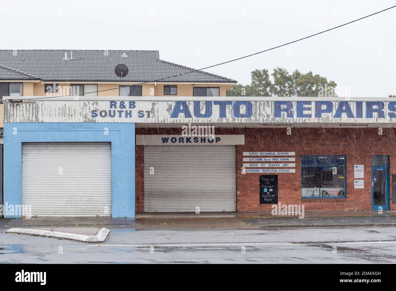 An Auto Repairs shop in a simple brick and steel roof building in Forster, New South Wales, Australia in pouring rain Stock Photo