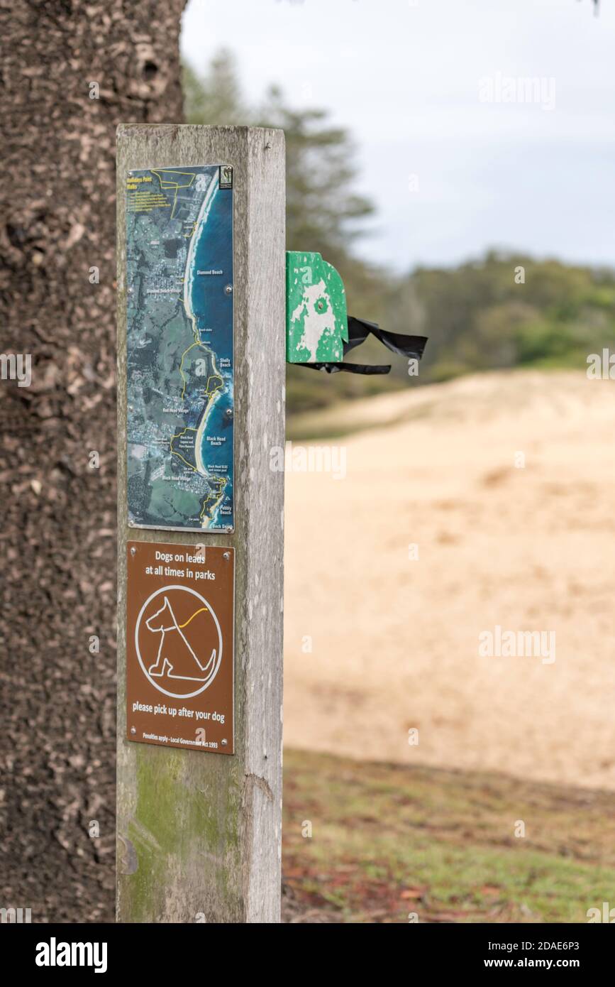A signpost size sign providing a mini map, a warning to do owners to keep dogs on a leash and a dog poo bag dispenser. Stock Photo