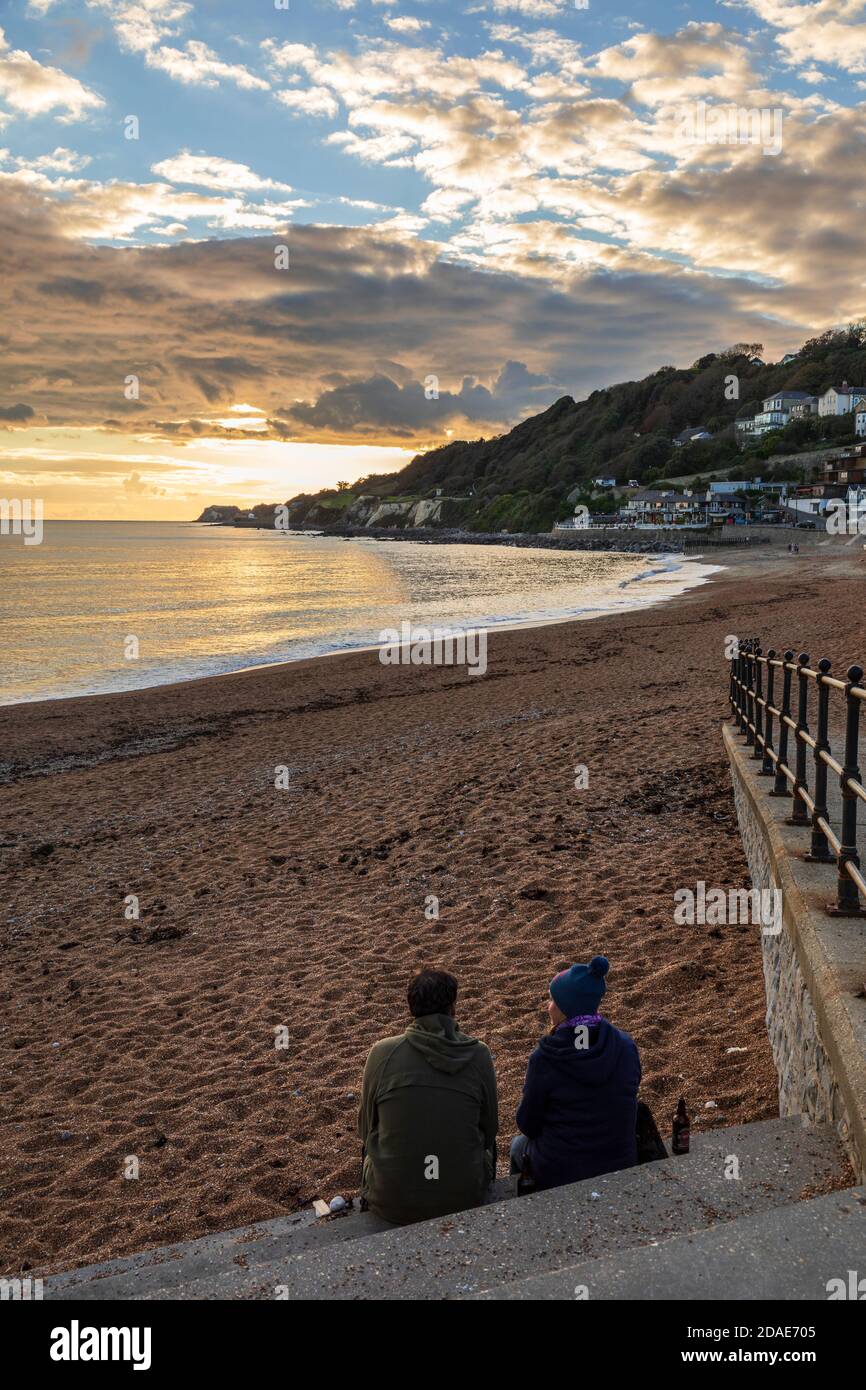 A couple watching the sun set over the beach at Ventnor, Isle of Wight Stock Photo