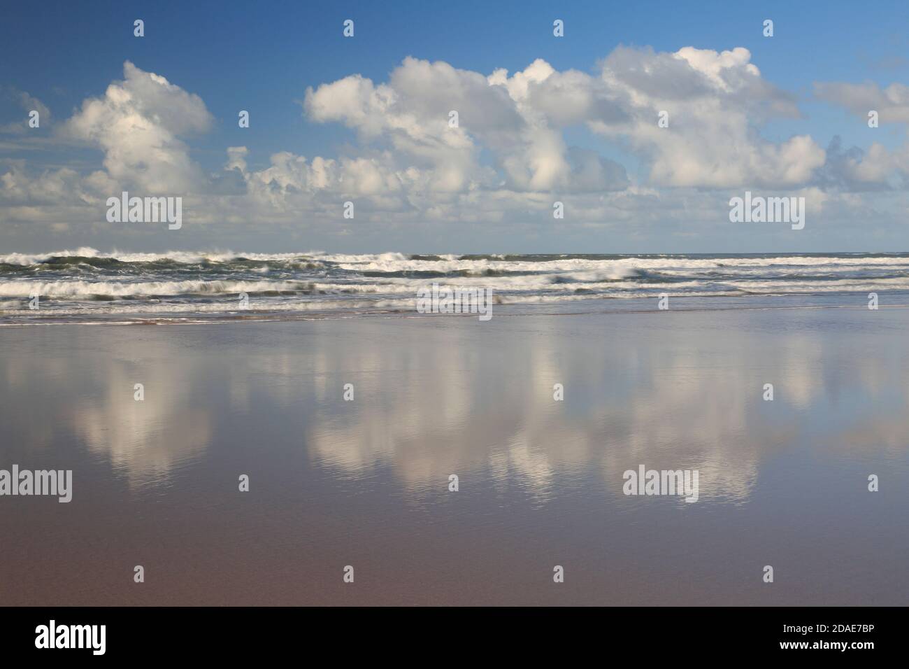 White fluffy clouds with reflections on Sandymouth beach Cornwall Stock Photo