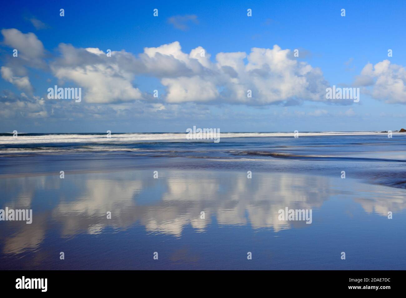 White fluffy clouds with reflections on Sandymouth beach Cornwall Stock Photo