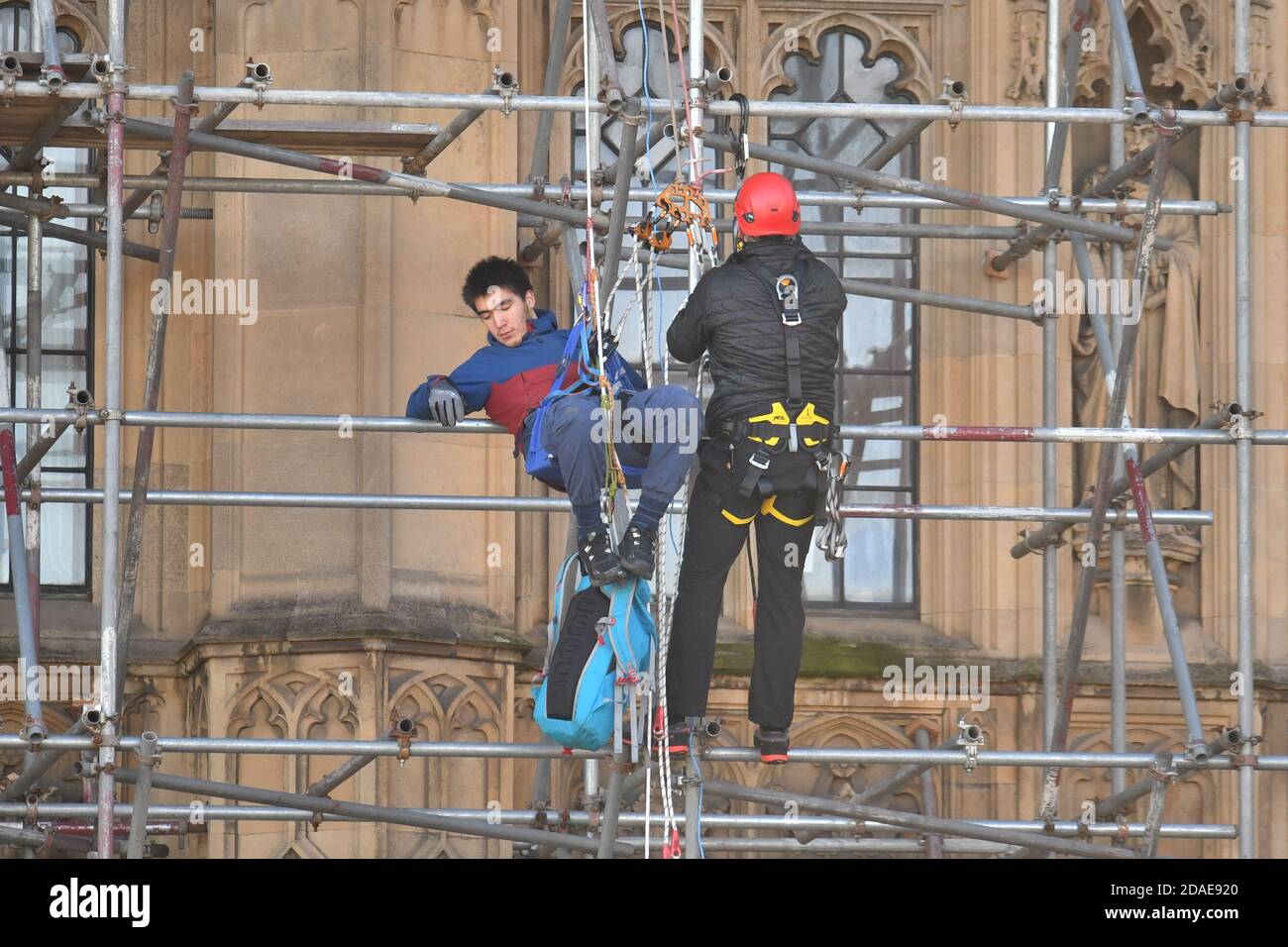 A protester from Action for Climate Truth and Reparations is removed after climbing the scaffolding outside the Houses of Parliament, London. Stock Photo