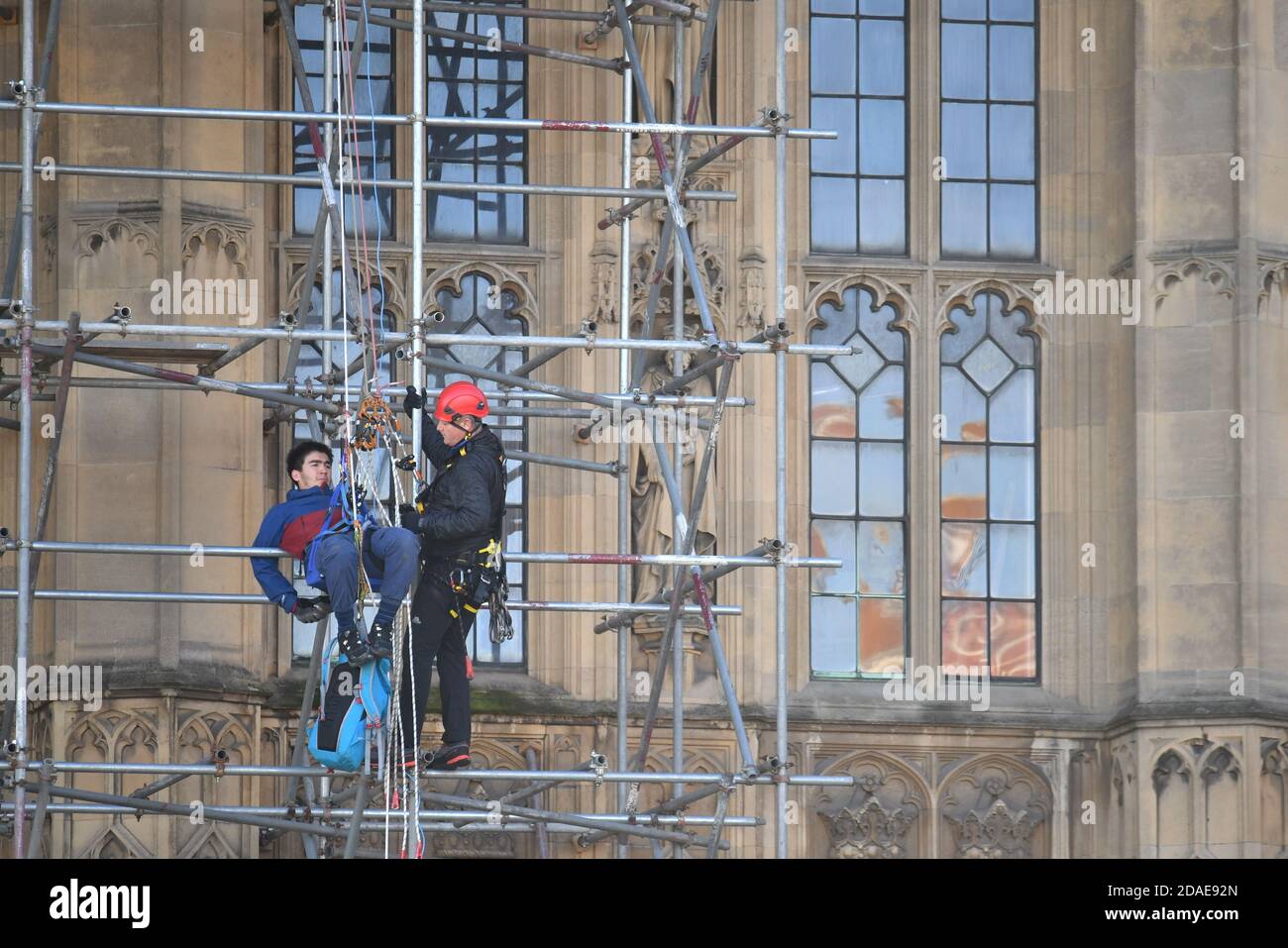 A protester from Action for Climate Truth and Reparations is removed after climbing the scaffolding outside the Houses of Parliament, London. Stock Photo