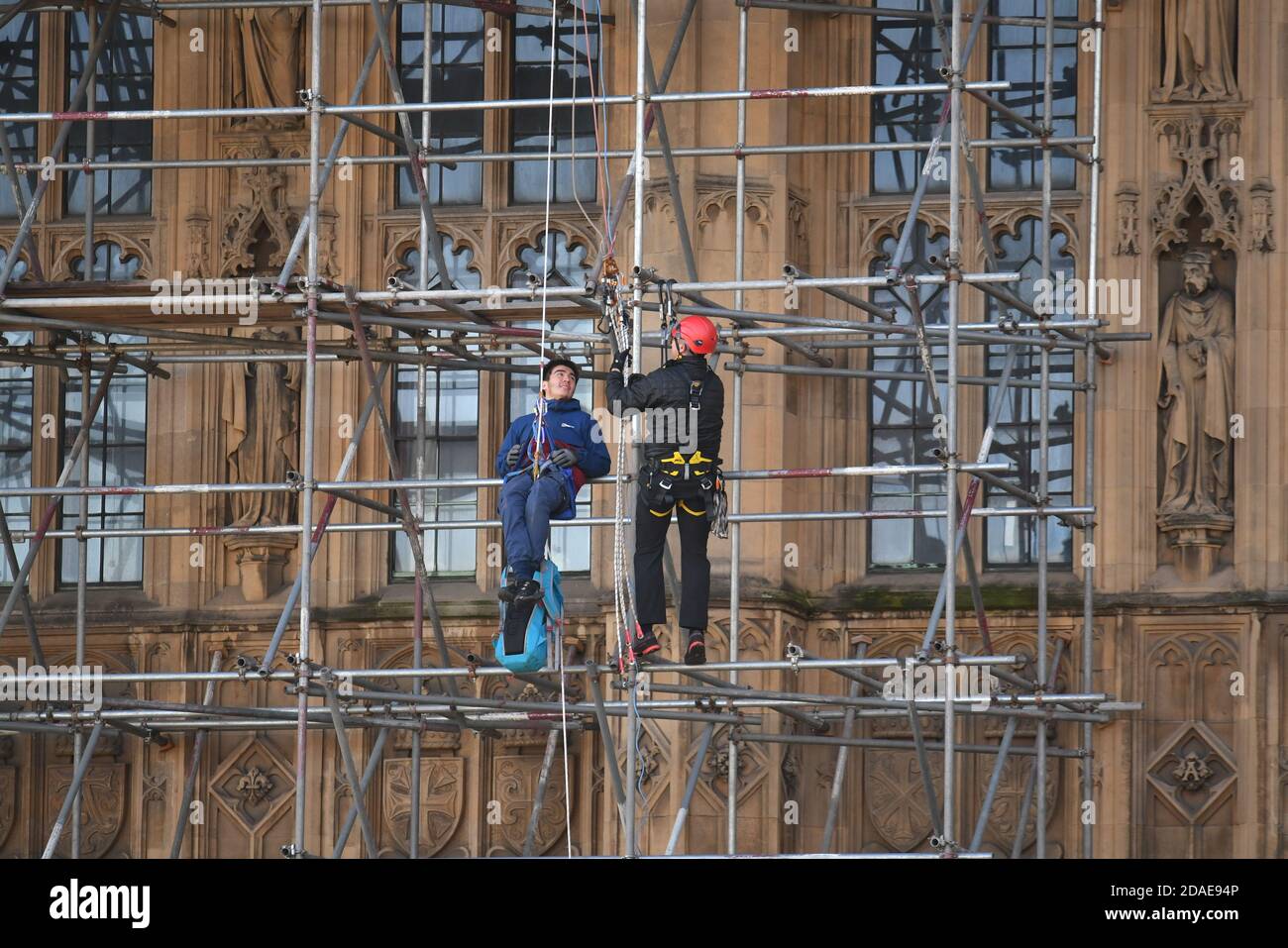 A protester from Action for Climate Truth and Reparations is removed after climbing the scaffolding outside the Houses of Parliament, London. Stock Photo