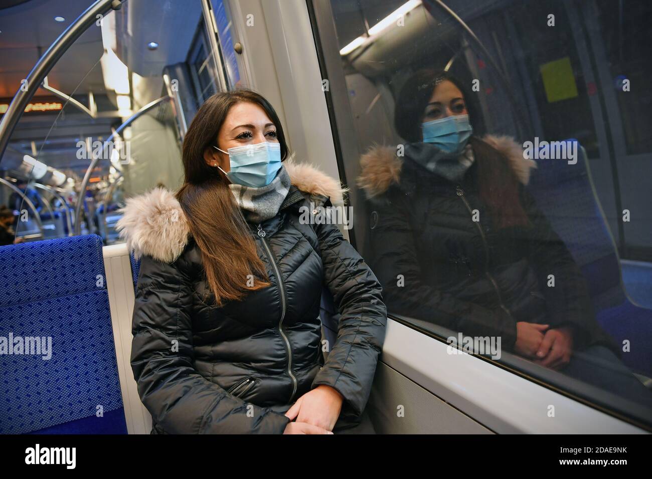 Mask compulsory in public transport. Young woman sitting in a train of the MVG with face mask, mask. U-Bahn Muenchen on November 11th, 2020. OEPNV, public transport, local transport, MVG, metro. MODEL RELEASED! | usage worldwide Stock Photo