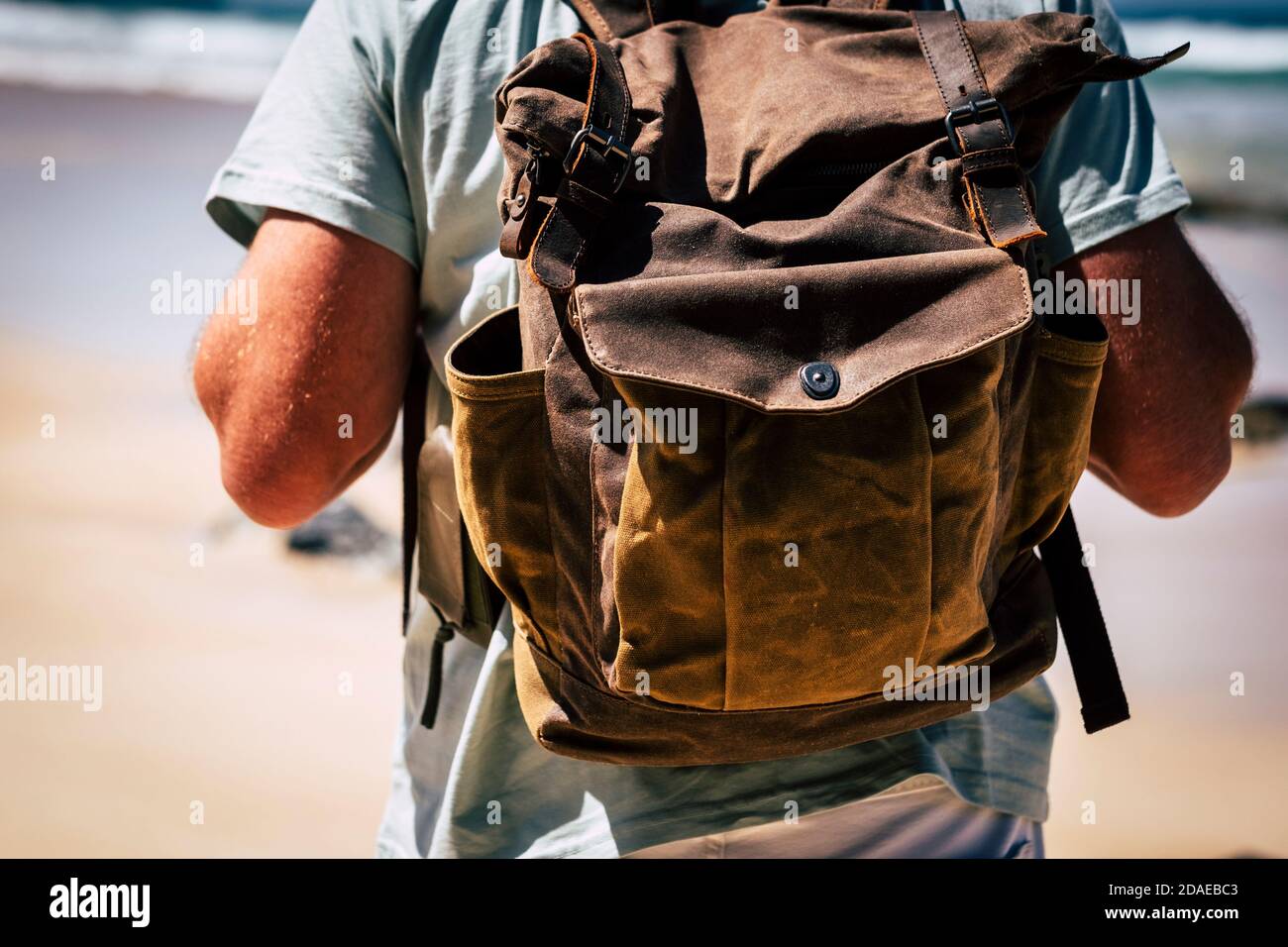 close up of a man with backpack - travel and adventure concept for backpacker people - beach and sea shore in background - alternative vacation summer time Stock Photo