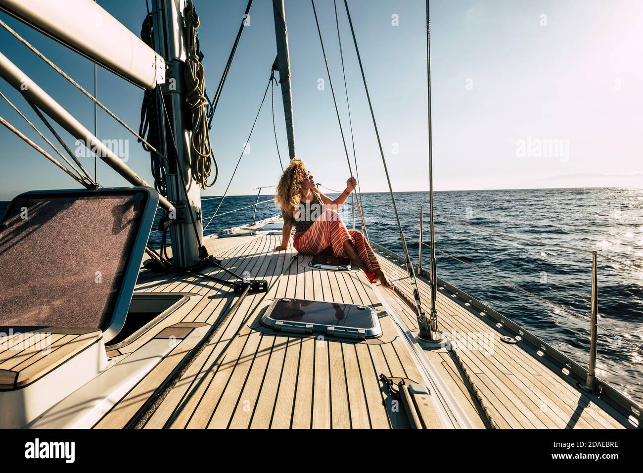Beautiful young woman enjoy summer holiday vacation or excursion on sailboat with sun and ocean around - people enjoying life and lifestyle - travel and transport on sea concept Stock Photo