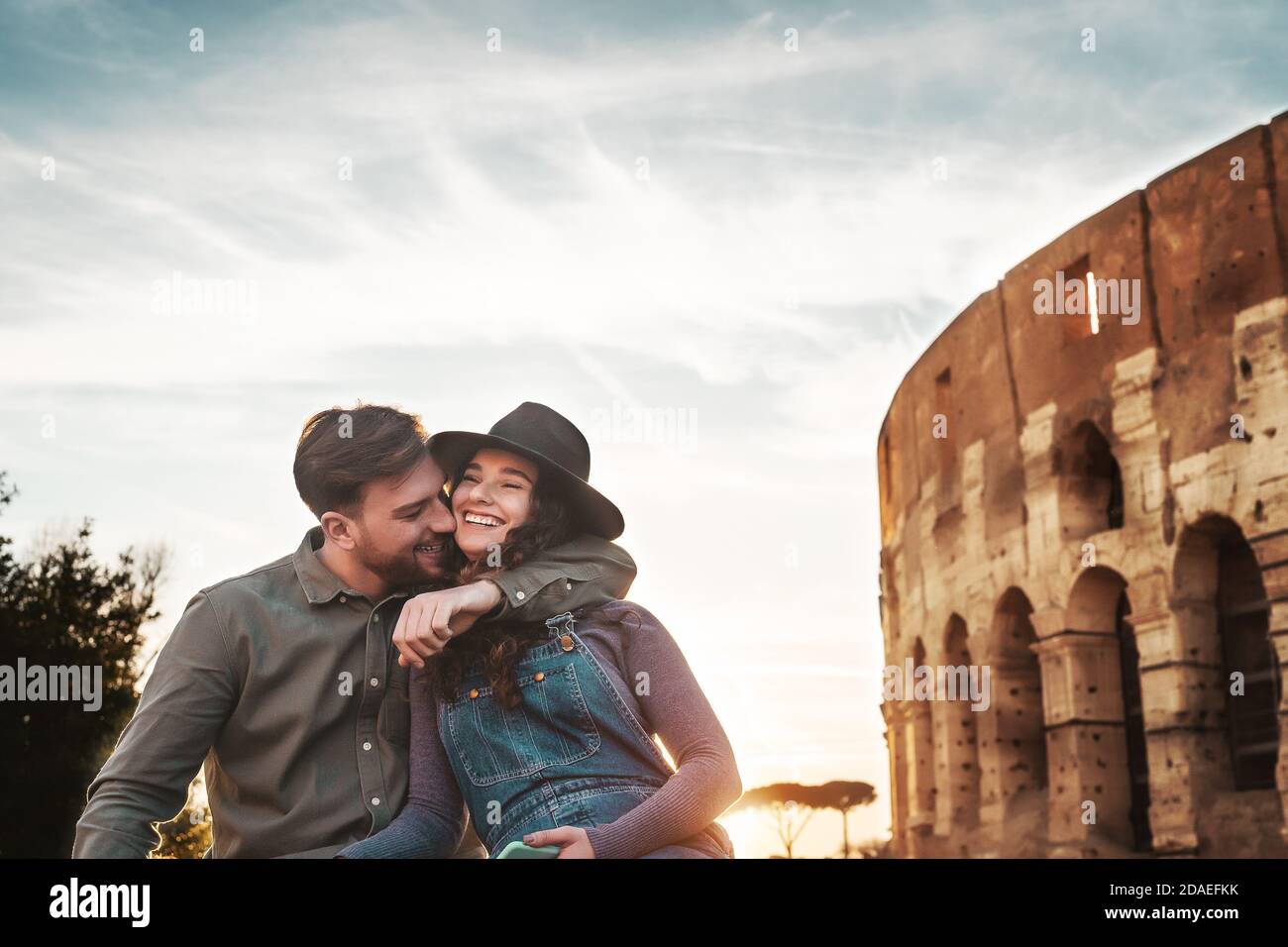 Young couple having positive emotions in Rome Colosseum - Happy lovers romantic moments during vacations in Italy Stock Photo