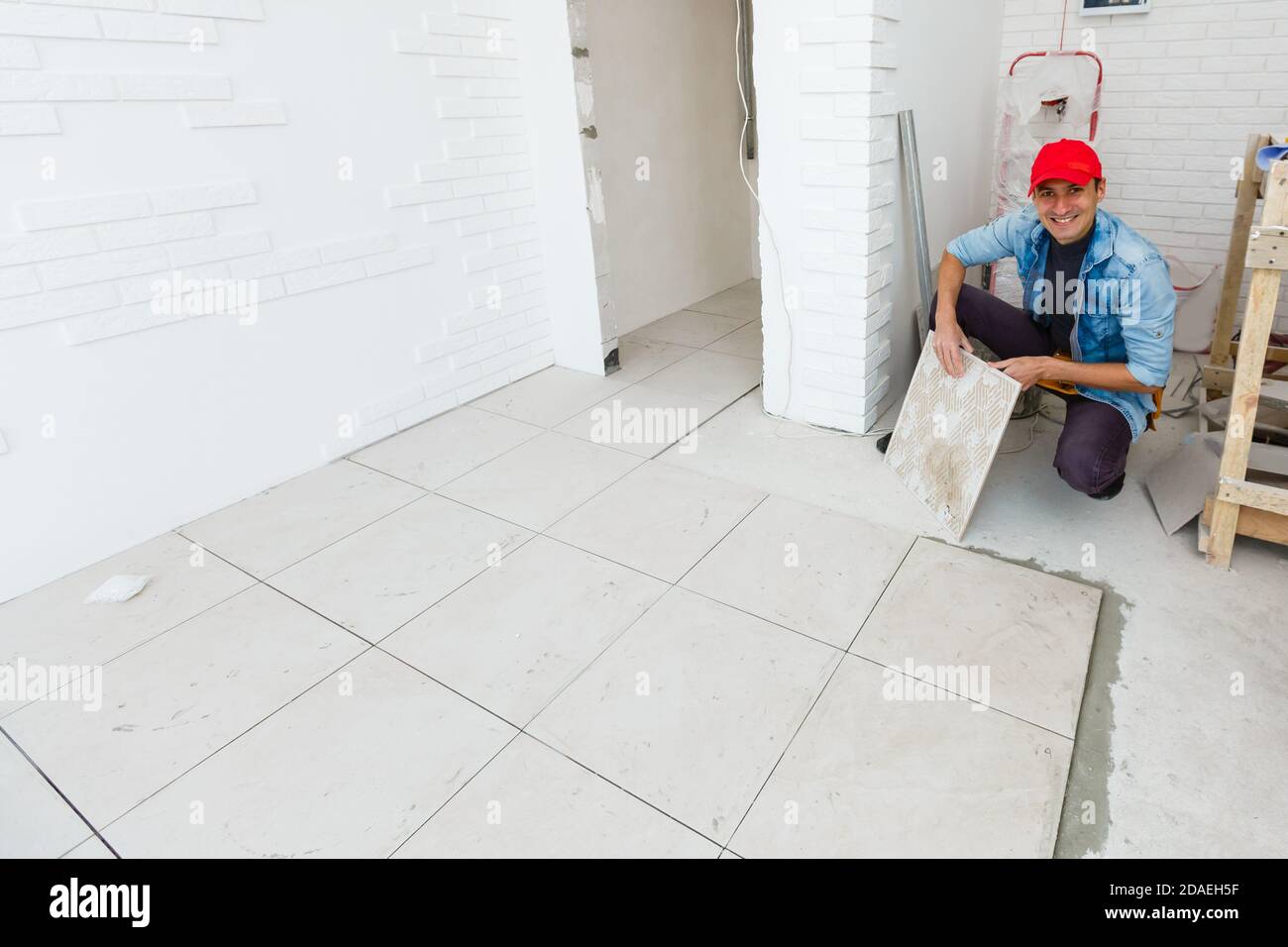 master is installing floor ceramic tile in a room, pressing down and