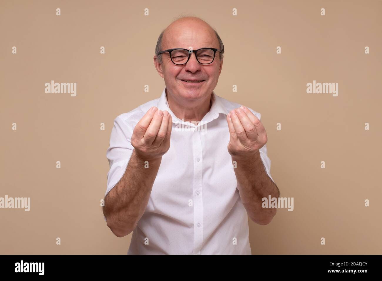 Bald handsome senior man looking angry showing italian gesture. Stock Photo