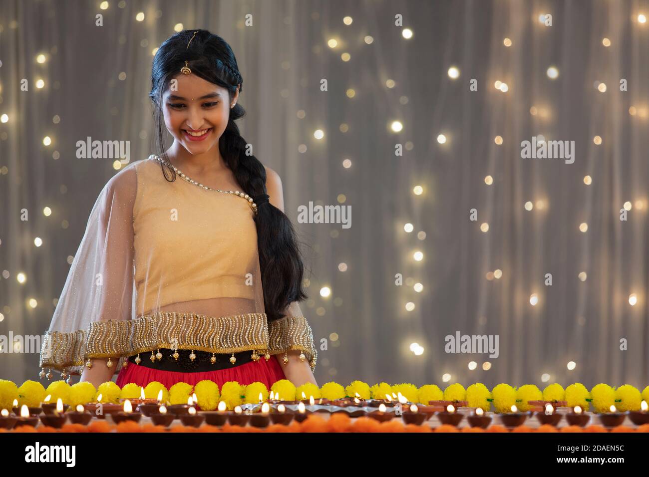 Beautiful young girl looking and smiling at Diwali decorations Stock Photo