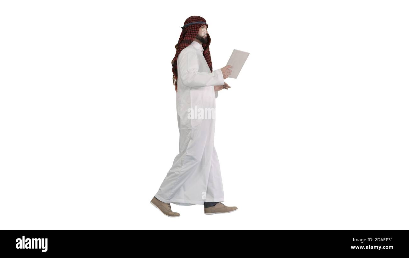 Sheikh using digital tablet and walking on white background. Stock Photo