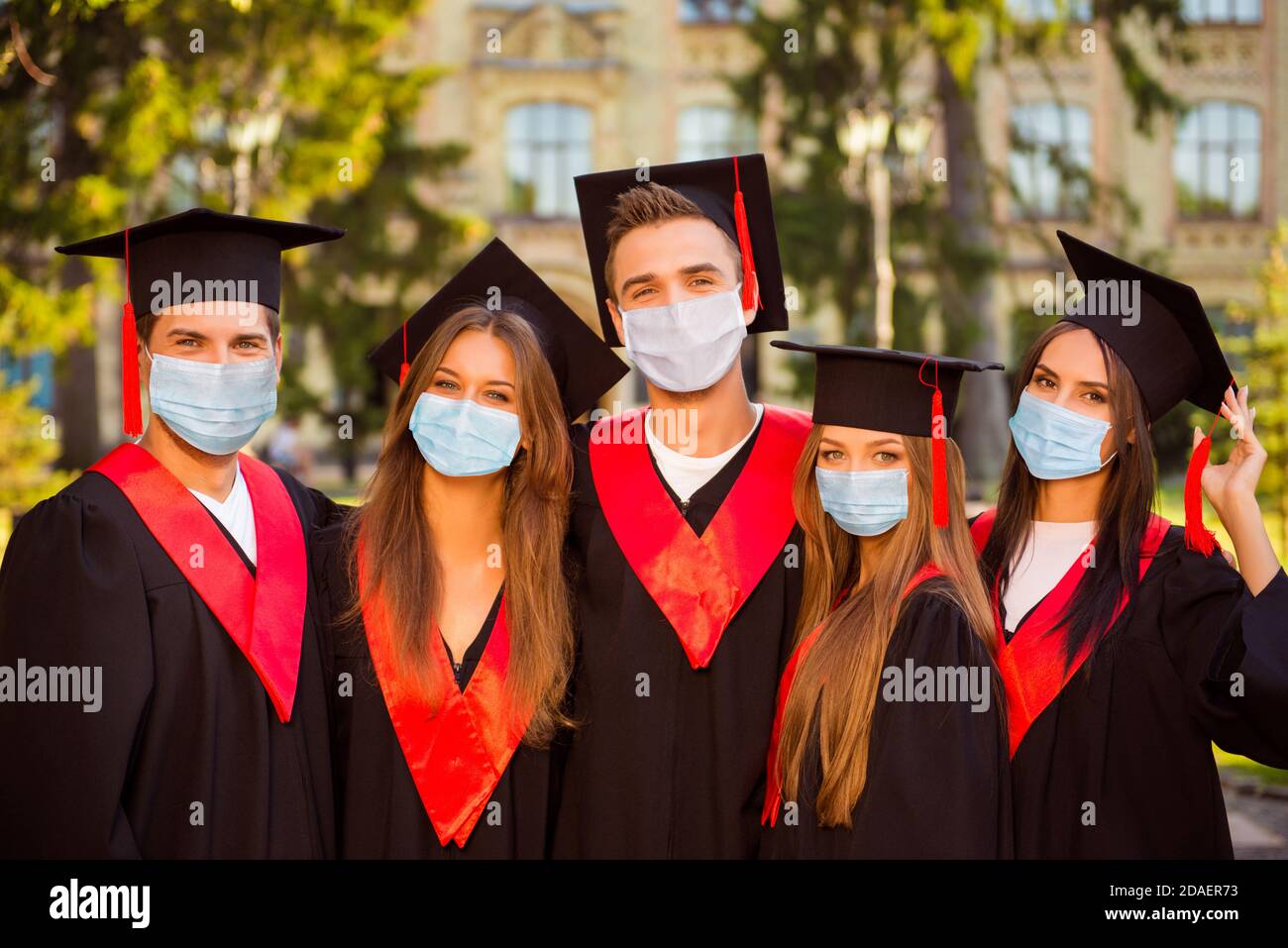 Photo portrait of five graduates in robes and hats with tassel wearing