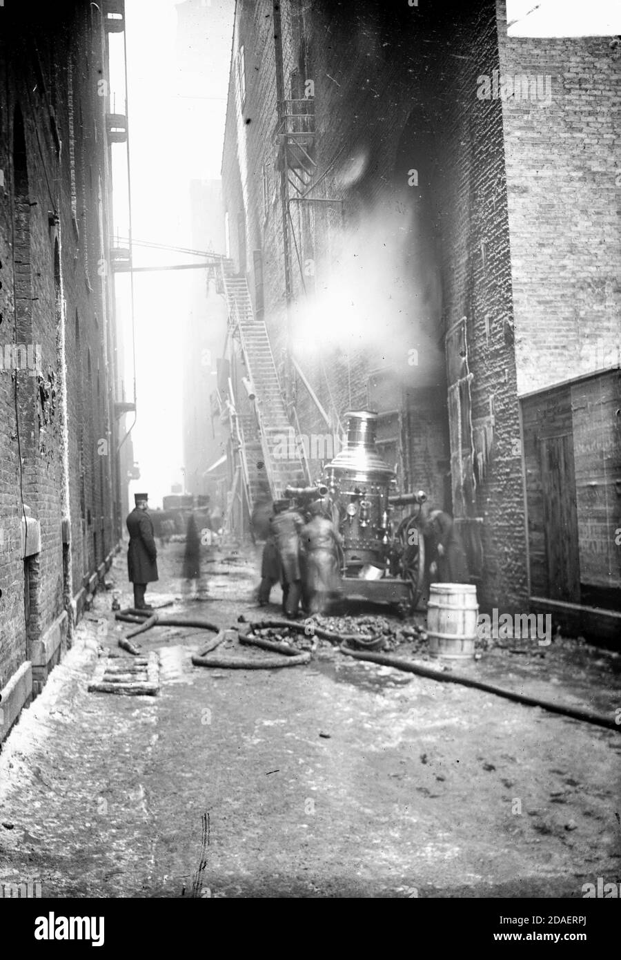 View of a fire engine and male firefighters in an alley during the Iroquois Theater fire, December 30, 1903, Chicago, Illinois. Stock Photo