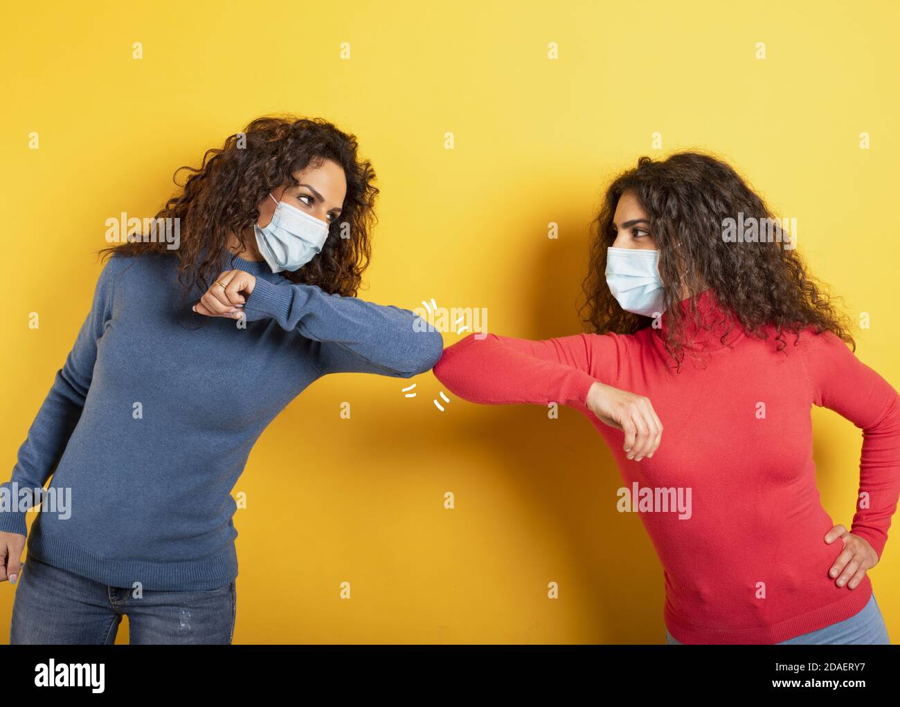 Friends greet each other while keeping their distance. Concept of codiv-19 rules to avoid pandemic. yellow background Stock Photo